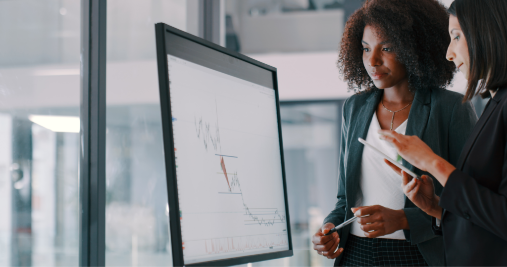 Two women looking at an interactive graph on a monitor. 