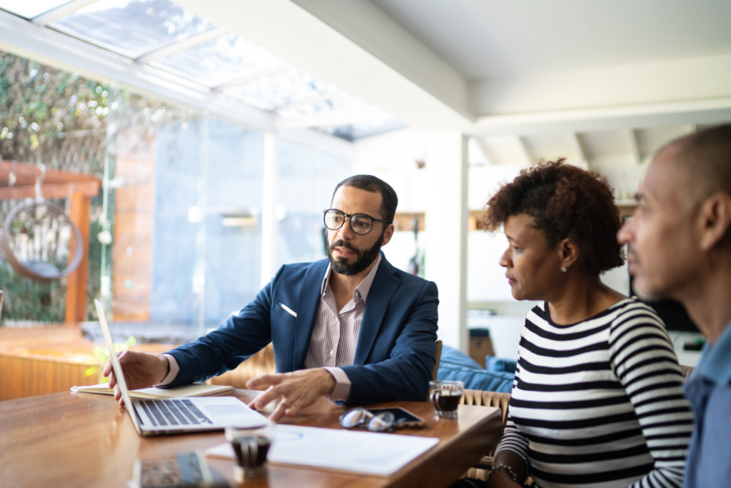 A business man using his computer to help explain a concept to a couple.