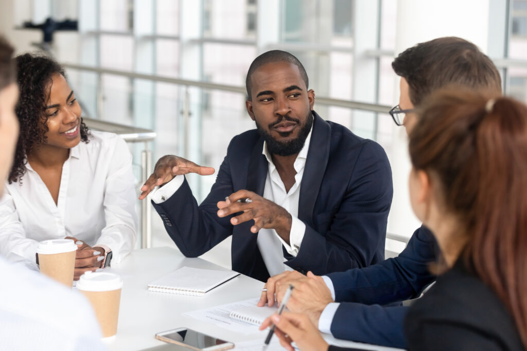 Millennial employees gathered in boardroom for training, black boss ceo leader leading corporate team during seminar learning at modern office. Internship and leadership coaching and education concept