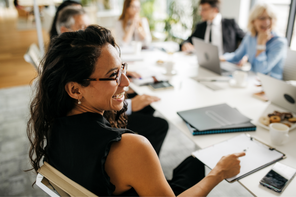 A CEO woman laughing at a board meeting. 