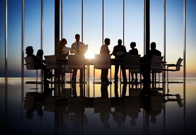 Silhouette of a board meeting while the sun is setting behind them. 