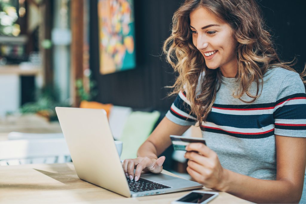 Woman smiling as she makes a purchase on her computer.