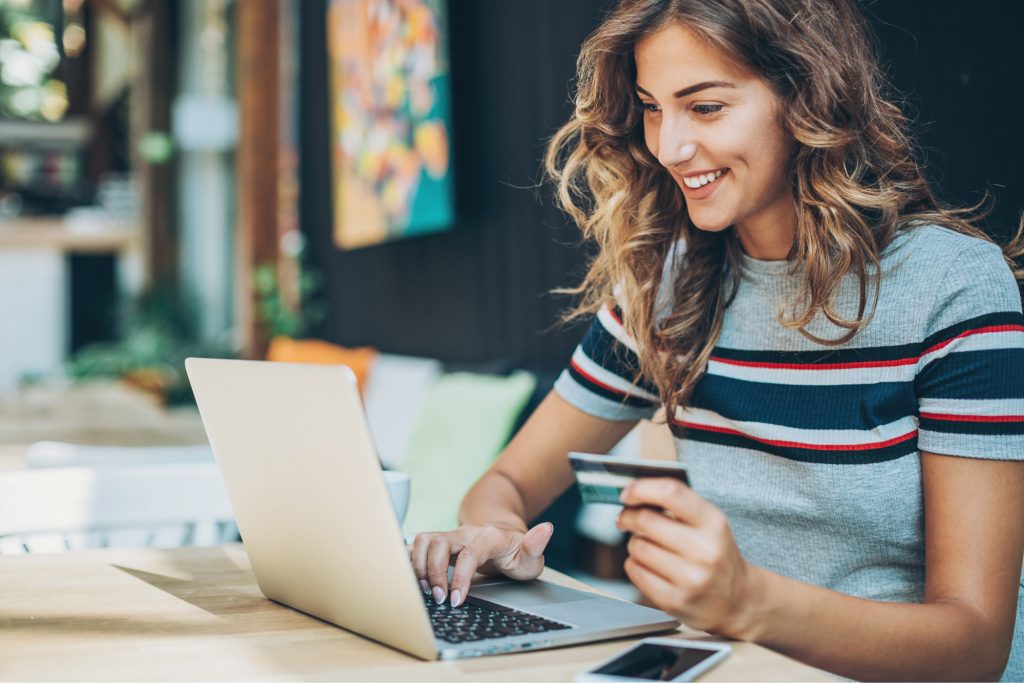 Woman smiling as she makes a purchase on her computer. 