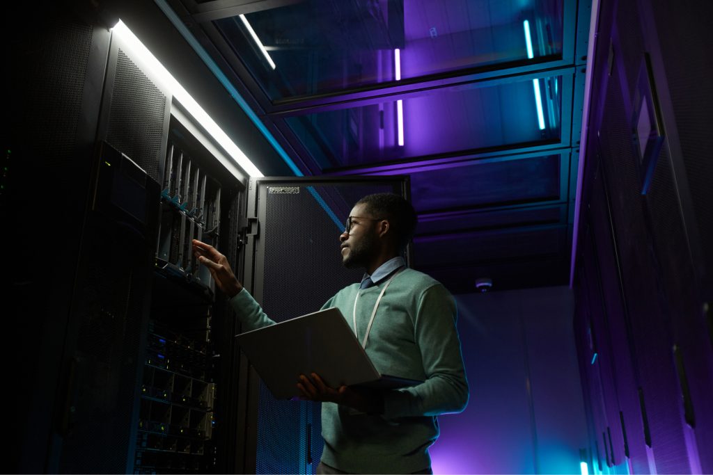 Man diagnosing a stack of computers with an iPad. 