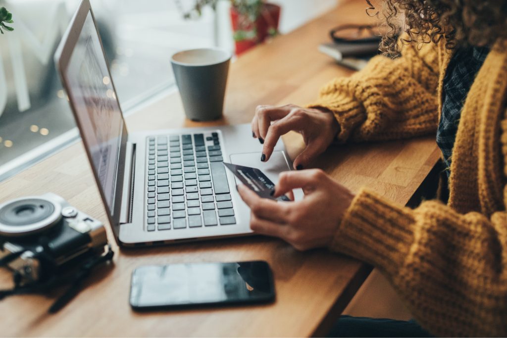 Woman typing in her card details for a purchase on her computer. 