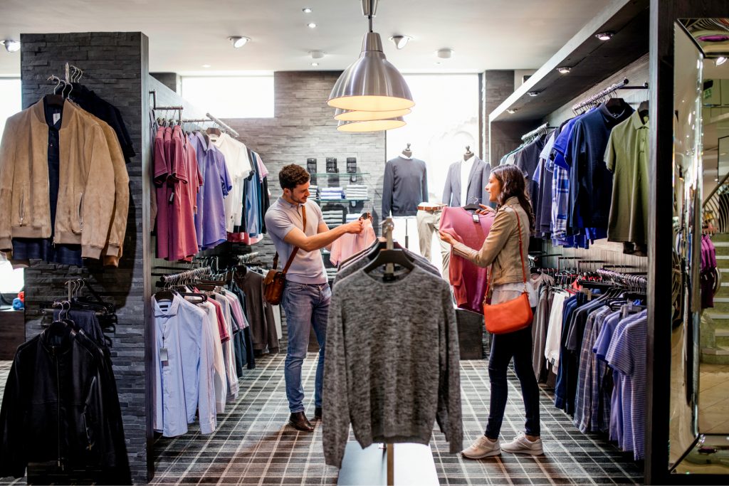 A couple looking at clothes in a retail store. 