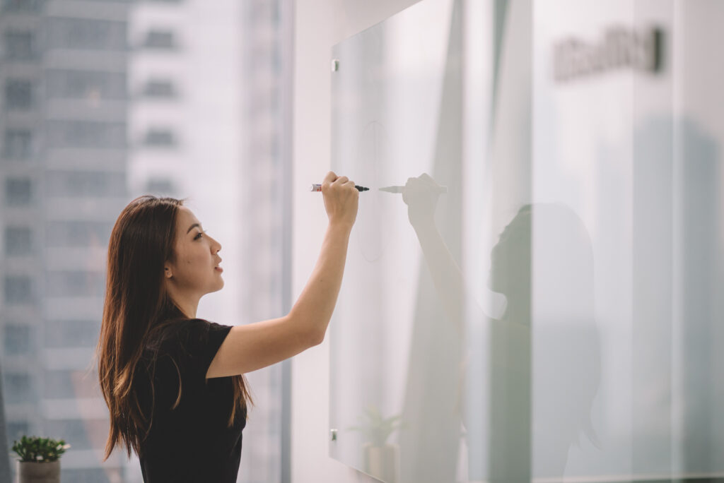 Woman writing on a white board. 