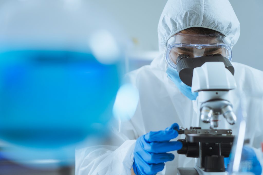 Scientist looking intently into a microscope at a Petri dish. 