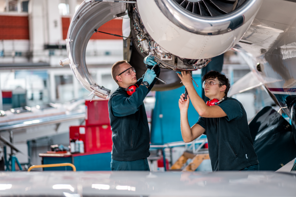 Two men working on the inside of a plane engine. 