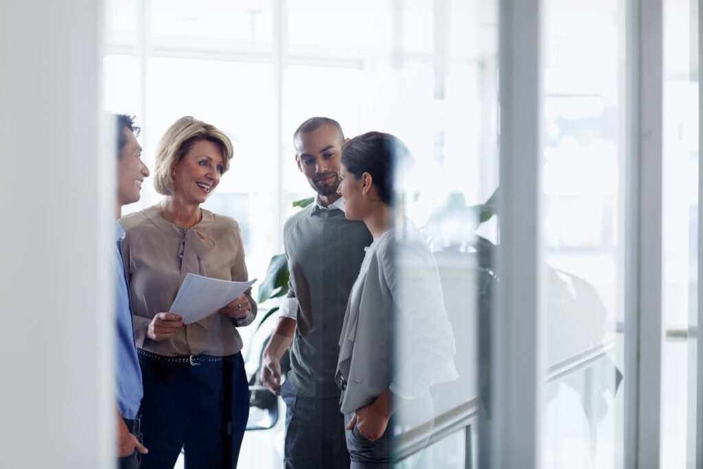 A woman addressing a group of people inside of an office.